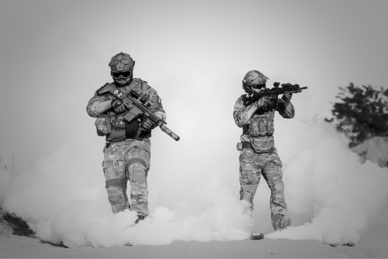 Two modern soldiers holding firearms wearing tactical gear surrounded by smoke from nearby cannisters