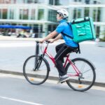 Restaurant delivery-person riding a bicycle on a city street