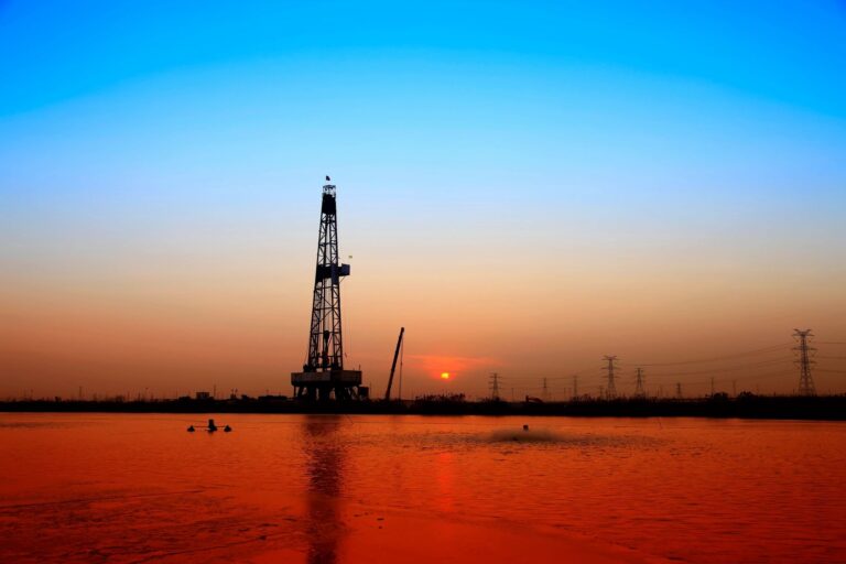 Large oil equipment close to water at sunset